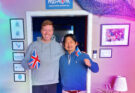 Orly Orlyson and Hiroshi Katta with the flags of Iceland and the UK in front of the Húsavík Eurovision Exhibition