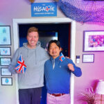 Orly Orlyson and Hiroshi Katta with the flags of Iceland and the UK in front of the Húsavík Eurovision Exhibition